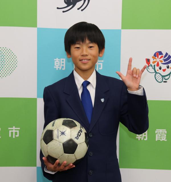 サッカーボールを持ち、「愛してる」の手話をする戸田さん