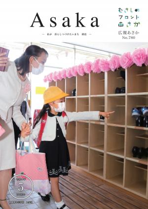 広報あさか５月号の表紙は、朝霞第十小学校入学式の様子です。新入生の女の子が、お母さんと一緒に自分の下駄箱を見つけ、指をさしています。