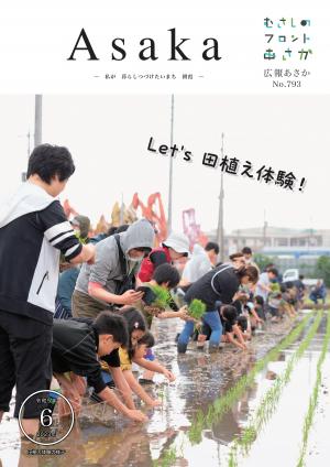 広報あさか令和５年６月号の表紙は、市内の田島地域で行われた、田植え体験の様子です。水が張られた田んぼの中に参加者の皆さんが一列となって、稲の苗を植えています。