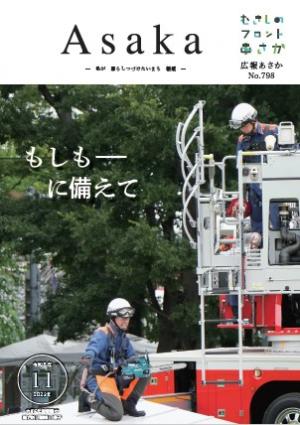 広報あさか令和5年11月号の表紙は、10年ぶりに行われた、朝霞市総合防災訓練の様子です。災害現場を再現した建物の屋根で、作業を行おうとしている県南西部消防局の職員が、指示を出しています。