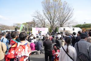 花まつりの様子の写真です。朝霞県土整備事務所の駐車場に特設ステージが設置され、出演者が演奏を披露しています。
