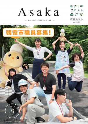 広報あさか令和７年８月号の表紙画像です。シンボルロードの緑を背景に、市職員が笑顔で写っています。