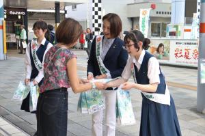 社会を明るくする運動啓発活動の様子の写真です。朝霞駅前広場で松下市長と四中の生徒が通行人に啓発グッズを配っています。