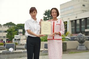 感謝状贈呈式の写真です。エムテック株式会社の担当者と松下市長が賞状を手に笑顔で写っています。