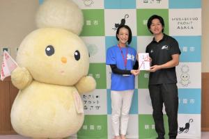 表敬訪問の様子です。松下市長、デフ陸上棒高跳びの北谷選手、市キャラクターぽぽたんがバックパネルを背に記念写真を撮っています。