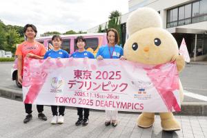 デフリンピックPR来庁時の写真です。PRカーを背に、市内在住のデフリンピック出場選手と松下市長、市キャラクターぽぽたんが写っています。