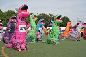 スポーツ大会の様子の写真です。ティラノサウルスレースに参加するため、松下市長が専用スーツを着込んでスタートラインに立っています。