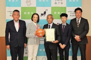 バスケットボール寄贈感謝状贈呈式の記念写真です。市長がバスケットボールを、日建総業株式会社の本部長が感謝状をそれぞれ手にし写っています。