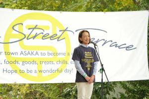 アサカストリートテラスオープニングセレモニーの写真です。ストリートテラスの横断幕の前で、松下市長があいさつを行っています。