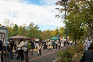アサカストリートテラスの様子です。シンボルロードの歩道に出店が立ち並び、参加者が食べ物やクラフト作品などを購入しています。