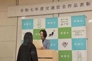 表彰式の様子です。市長が表彰を受ける児童の前で、表彰状を読み上げています。