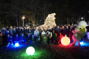 冬のあかりテラスの点灯式記念写真です。シンボルロード舗装広場付近に設置された、ライオン型のイルミネーションの前で、市長を含む協賛者・企業の方々が写っています。