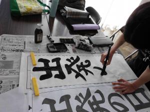 習字で出発の日を書いている写真