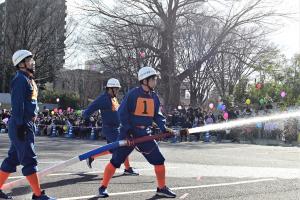 出初め式での放水の様子の写真です。消防団の隊員が放水銃を手に目標に向かって放水しています。