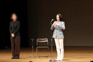 表彰・報告会であいさつをする市長の写真です。自己紹介時には手話を交えて話しています。