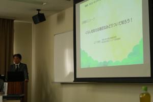 キックオフイベントでの朝霞のみどりに関する基調講演の様子です。スライドをスクリーンに投影し、あさかのみどりに関する内容を紹介しています。