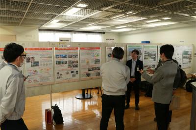 パネルの前で、担当者が説明をしている写真です。