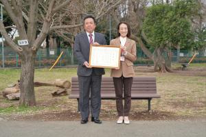 寄贈式の記念写真です。株式会社林土木の社長と松下市長が、感謝状を手にして、寄贈されたベンチをバックにして写っています。