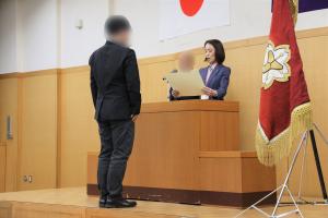 辞令交付式等の様子の写真です。市長が壇上で賞状を読み上げ、消防団員に手渡しています。