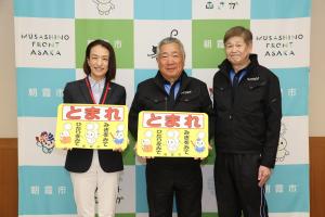 感謝状贈呈式の記念写真です。松下市長と代表取締役社長、取締役と一緒に、交通安全啓発路面シールを手にして写っています。