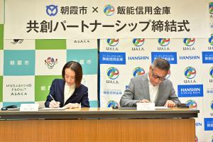 パートナーシップ締結式の様子の写真です。市長・飯能信用金庫理事長が締結書にサインをしています。