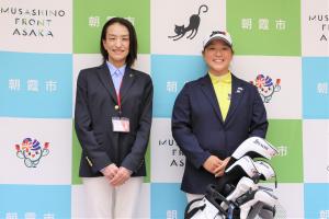 表敬訪問の記念写真です。市長と斎藤選手がゴルフクラブのセットを前に笑顔で写っています。