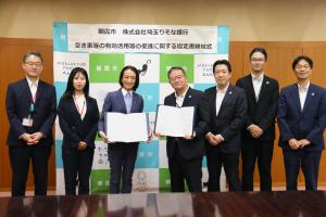 協定書締結式の記念写真です。松下市長と埼玉りそな銀行の代表者が協定書を手に笑顔で写っています。