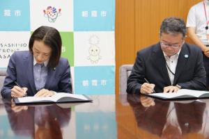 協定書締結式の様子の写真です。松下市長と埼玉りそな銀行の代表者が協定書に署名しています。