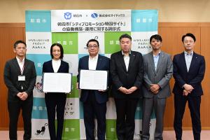 調印式の記念写真です。市長と株式会社サイネックスの代表の方々が協定書を手にして写っています。