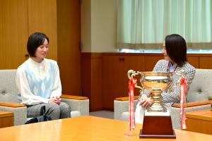 表敬訪問の様子の写真です。朝霞高校定時制の生徒と市長が優勝トロフィーを挟んで座り、談笑しています。