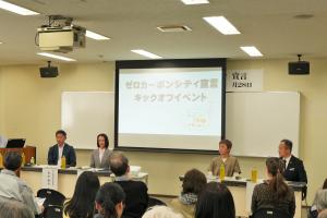 ゼロカーボンシティ宣言キックオフイベントの様子です。来場者の前で市長・市内事業者代表者・市民団体者がトークセッションを行っています。